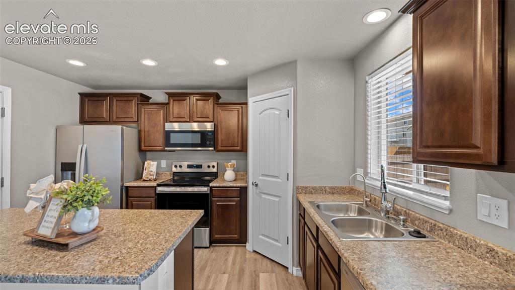 Image 16 of 43: Kitchen featuring wood-finish cabinetry, stainless steel appliances, lamina