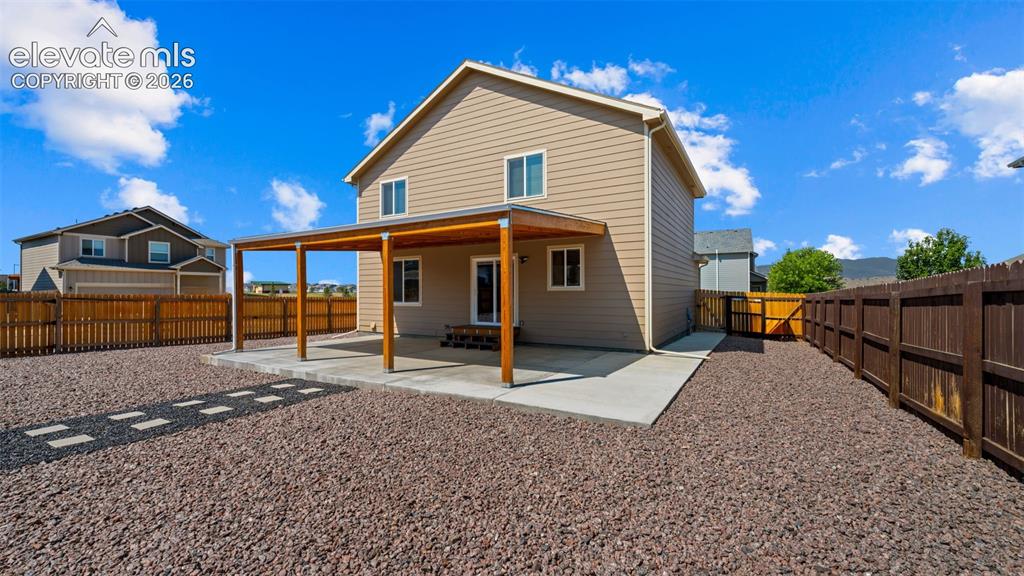 Image 29 of 43: Rear exterior featuring an expansive covered patio with wood support beams,
