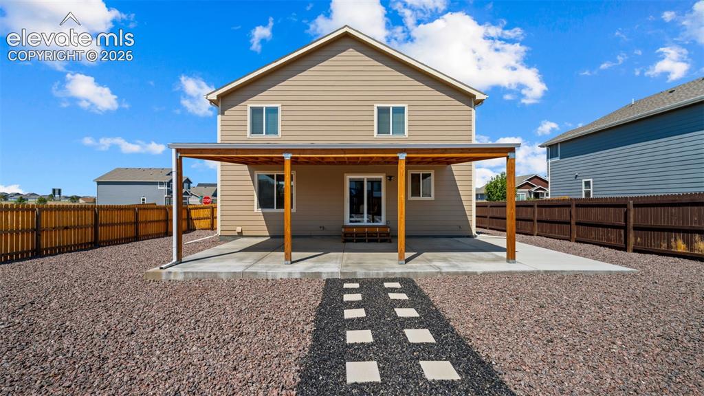 Image 30 of 43: Rear exterior featuring a covered patio with wood supports and a concrete s