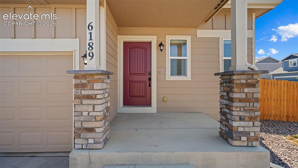 Image 4 of 43: Inviting front porch featuring stone-clad columns and a striking red entry