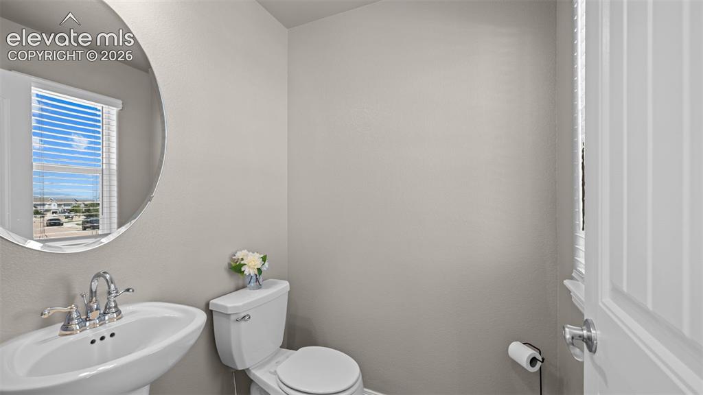 Image 5 of 43: Pedestal sink with chrome faucet, circular mirror, and window with horizont