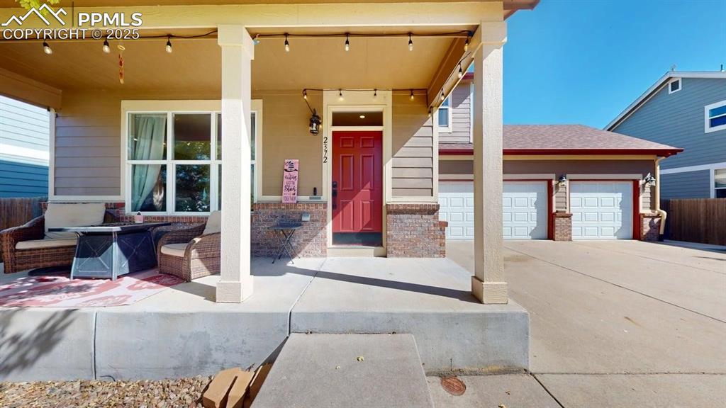 Image 2 of 14: Doorway to property with a porch, concrete driveway, and an attached garage