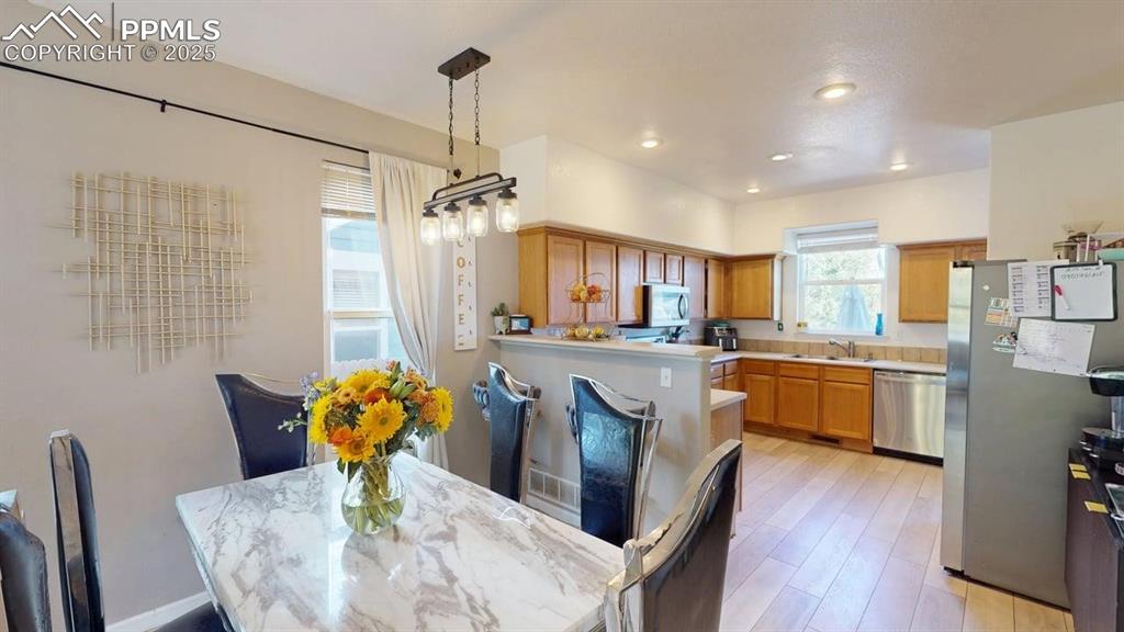 Image 6 of 14: Kitchen with brown cabinets, light countertops, appliances with stainless s