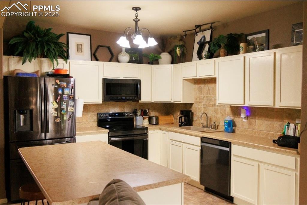Image 7 of 21: Kitchen featuring black appliances, decorative backsplash, light countertop