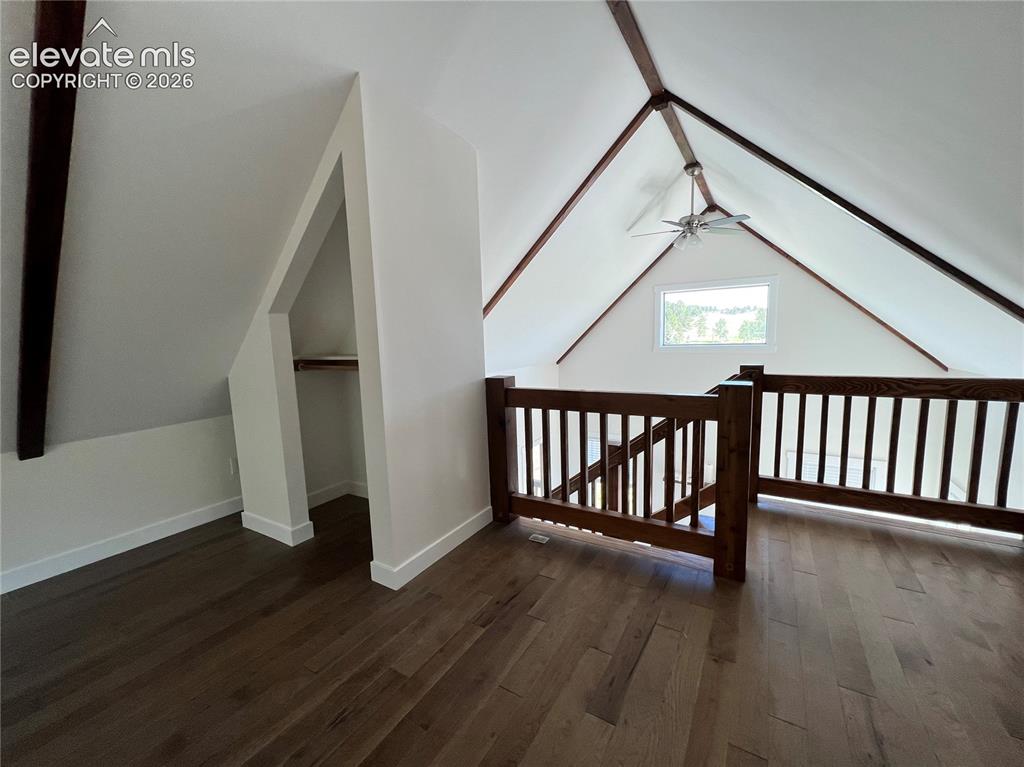 Image 24 of 43: Vaulted ceiling with exposed wood beams, wood-finish flooring, wood railing