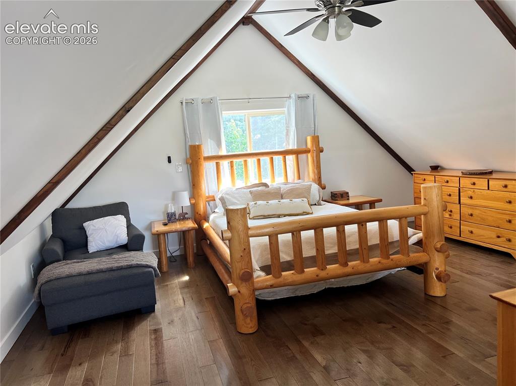 Image 25 of 43: Vaulted ceiling with exposed wood beams, wood-finish flooring, and a ceilin