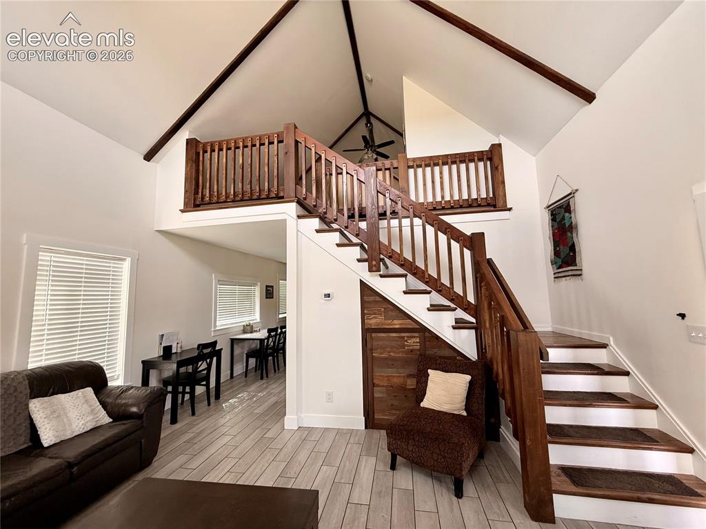 Image 28 of 43: Soaring vaulted ceilings with exposed beams, wood-finish flooring, and a pr