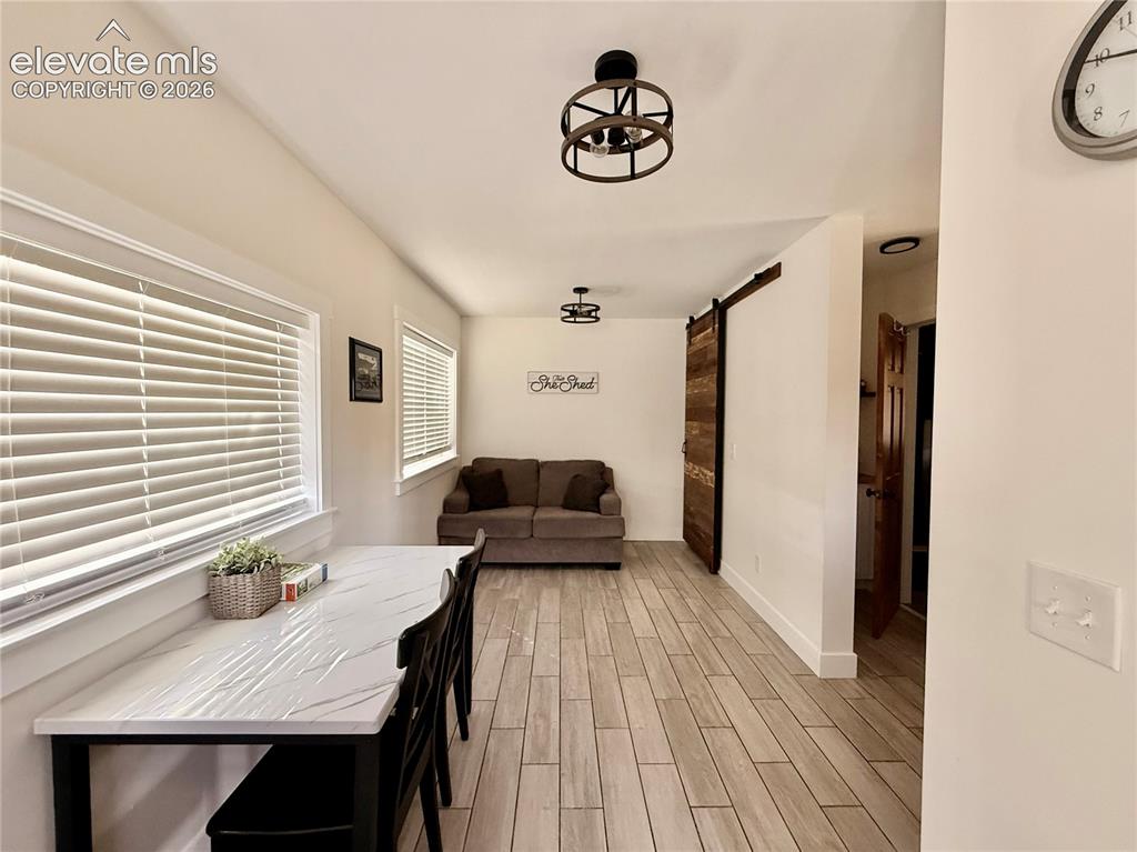 Image 31 of 43: Wood-finish flooring throughout, white framed windows, and a sliding wood-p