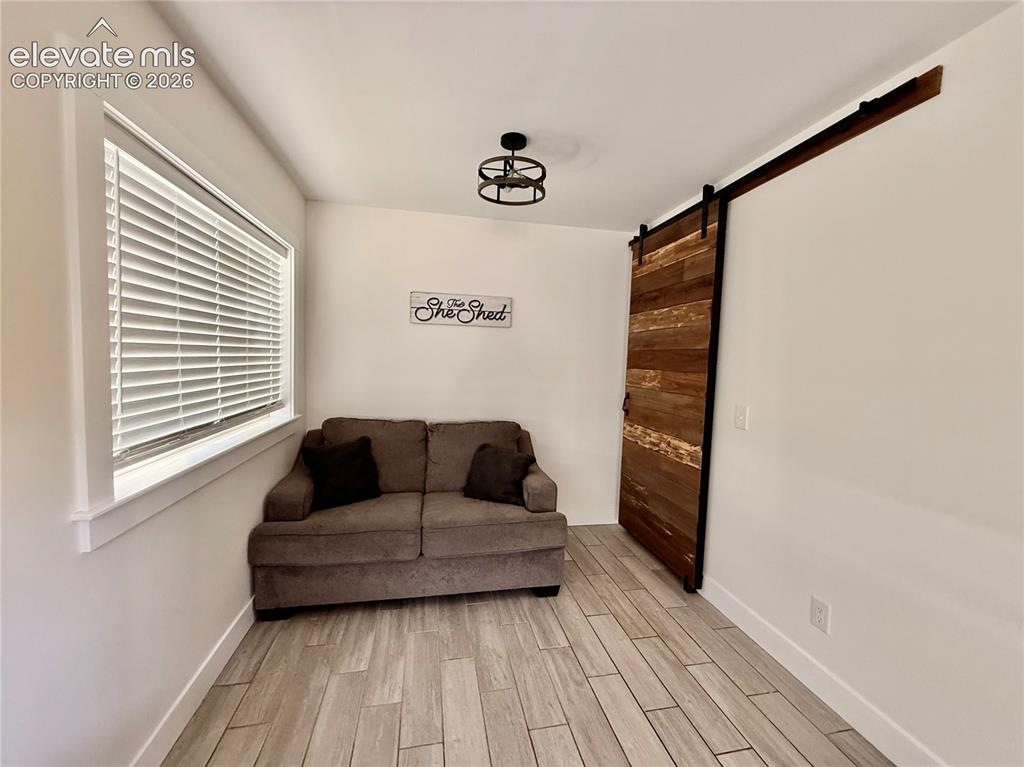 Image 32 of 43: Wood-finish tile flooring, a large window with blinds, a ceiling-mounted li