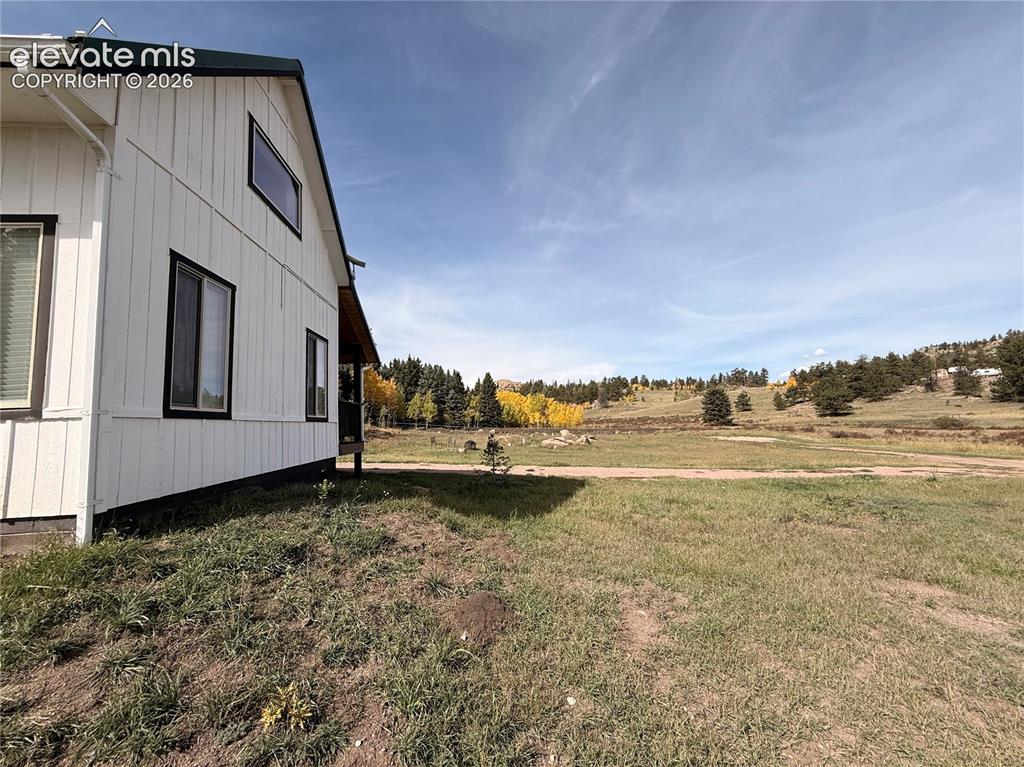Image 5 of 43: White vertical siding exterior with dark trim windows and a dark-pitched ro