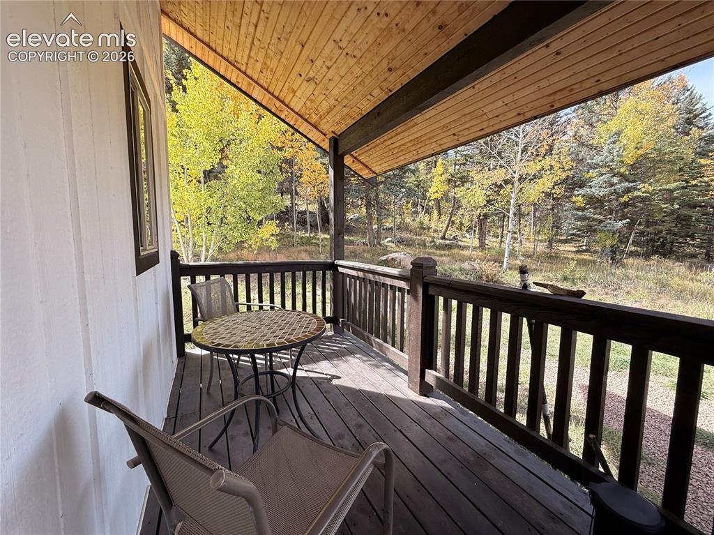 Image 6 of 43: Covered deck with wood flooring and railing