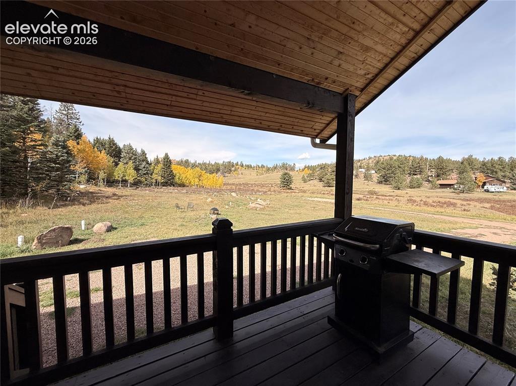 Image 7 of 43: Covered wood-plank deck with wood railing, featuring a vast natural landsca