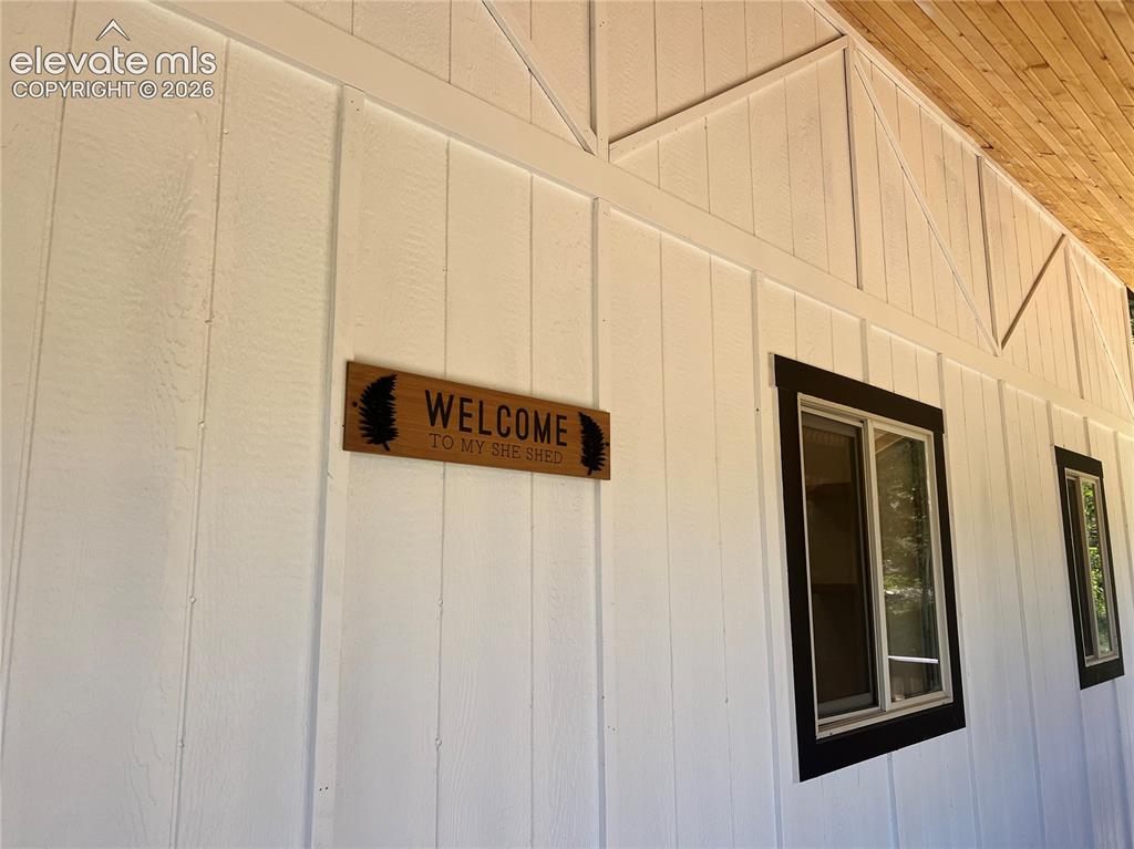 Image 9 of 43: White board and batten siding, dark-trimmed windows, and wood-finish soffit