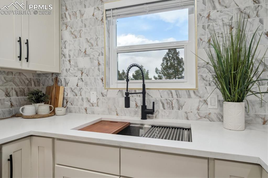 Image 10 of 44: Kitchen featuring a sink, white cabinets, backsplash, and light countertops