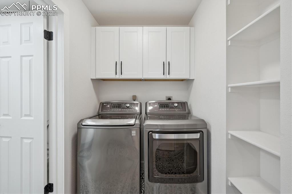 Image 12 of 44: Washroom featuring washing machine and dryer and cabinet space
