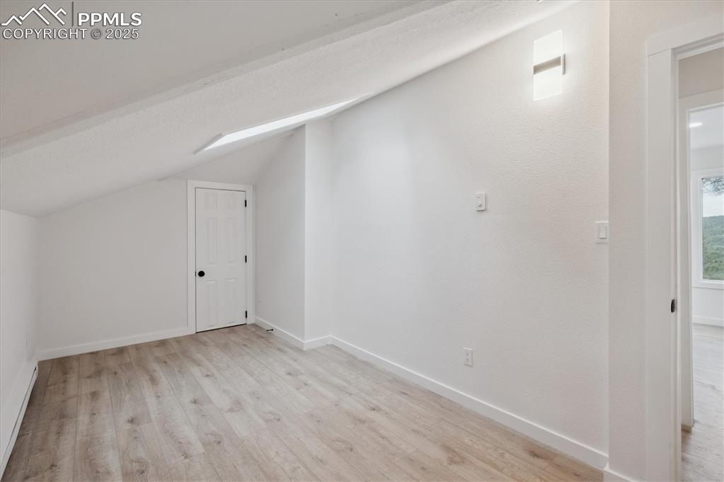 Image 19 of 44: Bonus room with vaulted ceiling, light wood-style flooring, and baseboards