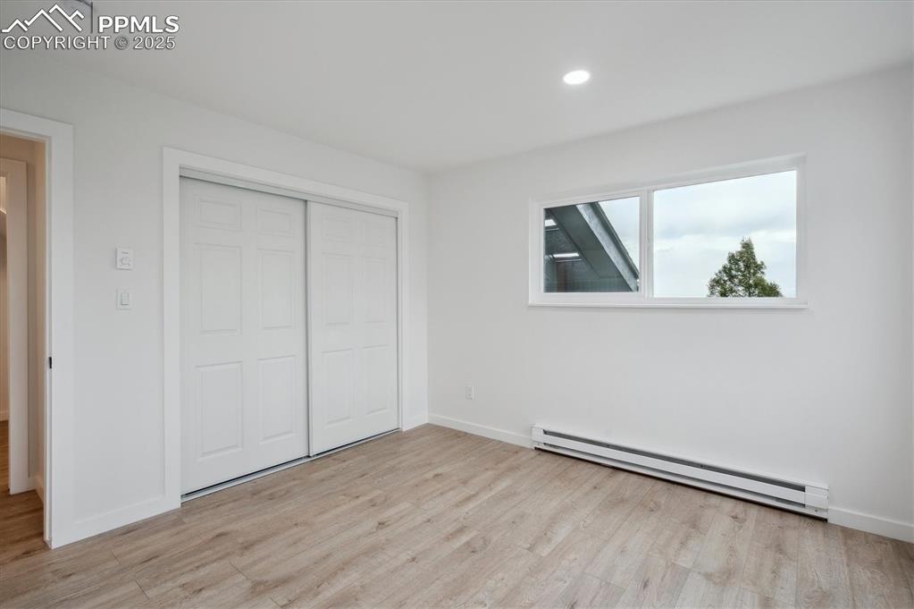 Image 21 of 44: Unfurnished bedroom with a baseboard radiator, light wood finished floors, 
