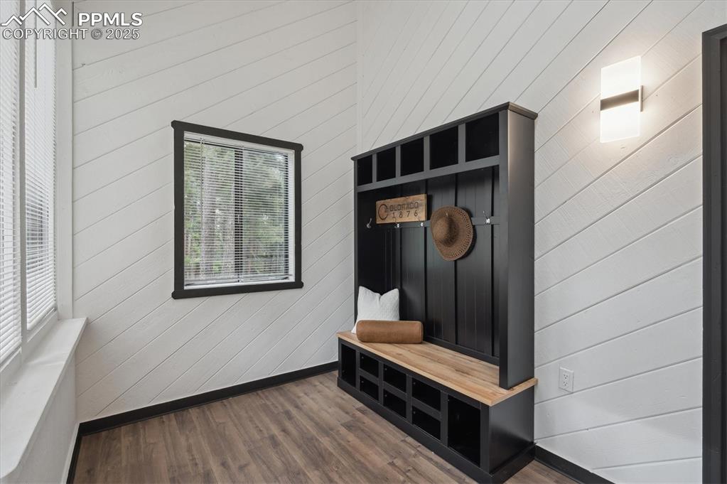Image 22 of 44: Mudroom featuring wooden walls, dark wood-style floors, and baseboards