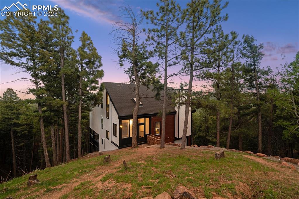 Image 37 of 44: Back of property at dusk with stucco siding and roof with shingles