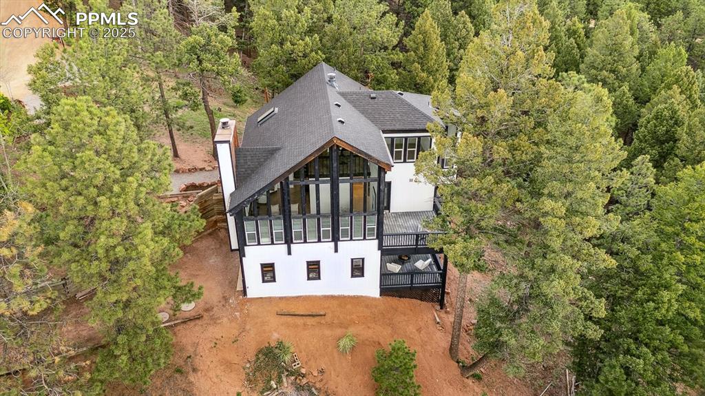 Image 43 of 44: Rear view of house with a shingled roof, a view of trees, a chimney, and st