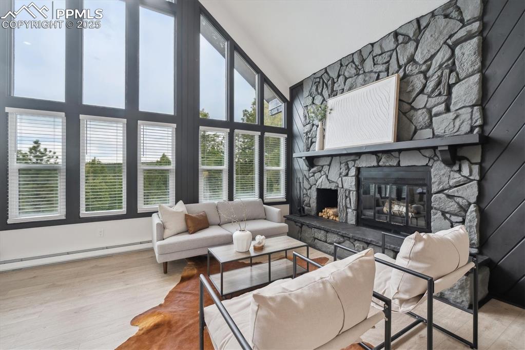 Image 5 of 44: Living area featuring a fireplace, a baseboard heating unit, wood finished 