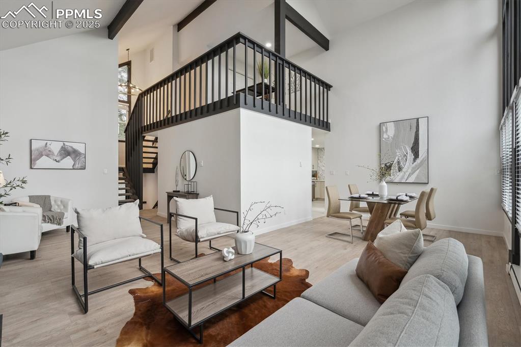 Image 7 of 44: Living room with high vaulted ceiling, beamed ceiling, stairs, baseboards, 