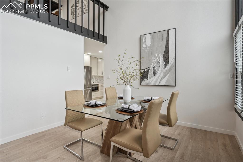 Image 8 of 44: Dining area with baseboards, light wood finished floors, and a high ceiling