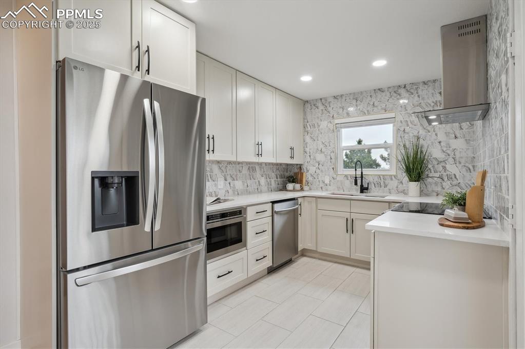 Image 9 of 44: Kitchen with stainless steel appliances, wall chimney exhaust hood, a sink,