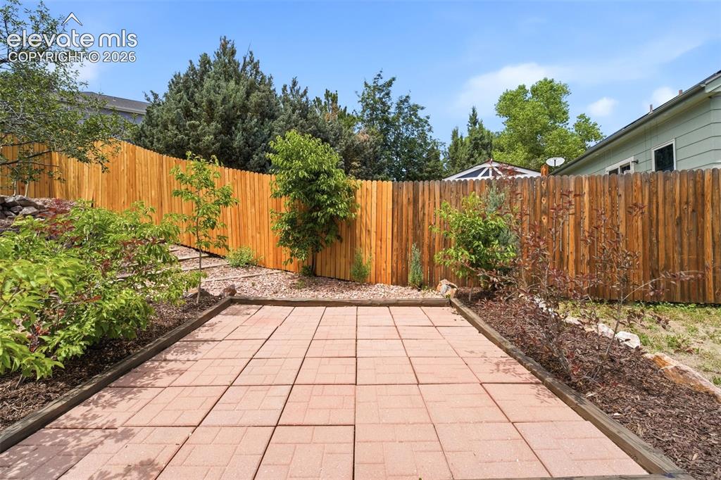 Image 25 of 30: Expansive backyard featuring a paver patio area with wood border, surrounde