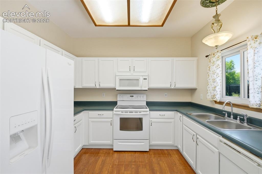Image 5 of 30: Kitchen featuring white cabinetry, wood-finish flooring, and a double basin