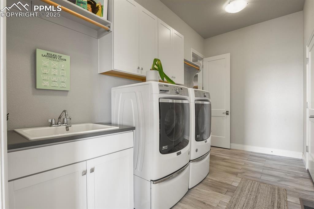 Image 29 of 50: Main level laundry room with sink and access to primary walk-in closet and