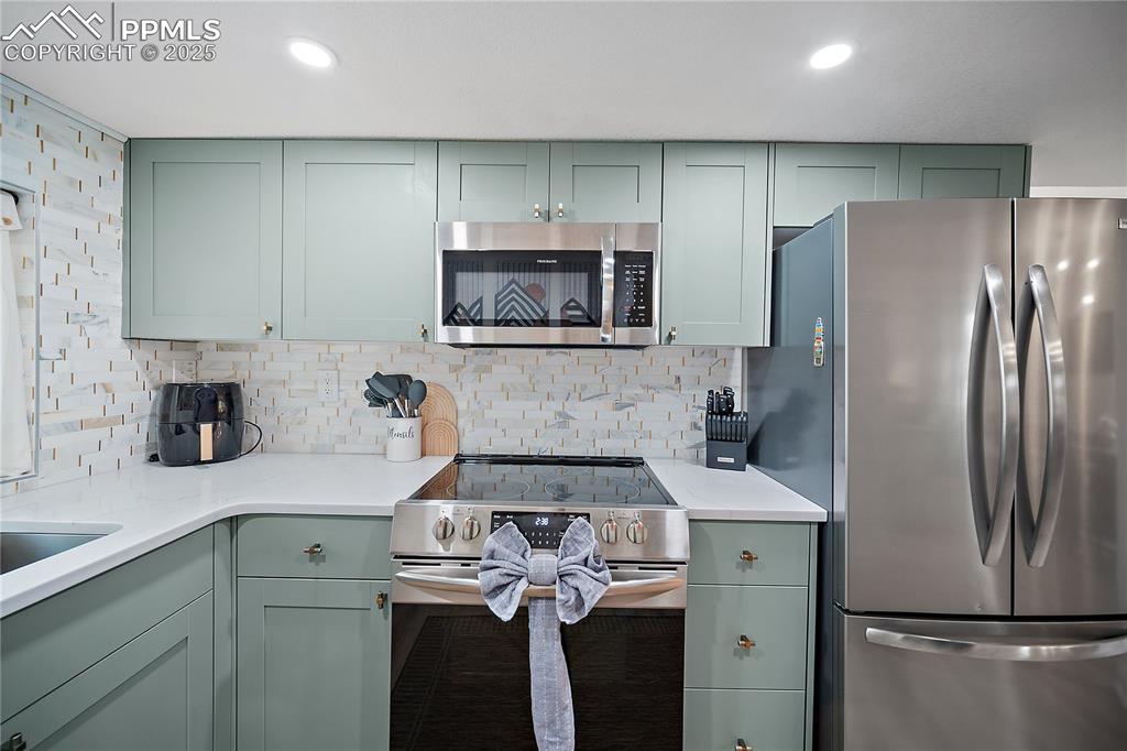 Image 10 of 47: Kitchen featuring decorative backsplash, green cabinetry, and stainless ste