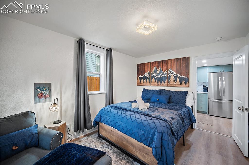 Image 12 of 47: Bedroom with freestanding refrigerator and light wood-style flooring
