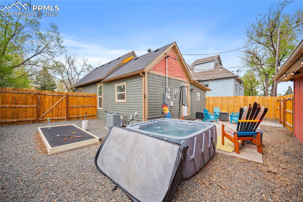 Image 18 of 47: Back of house featuring central air condition unit, a fire pit, a fenced ba