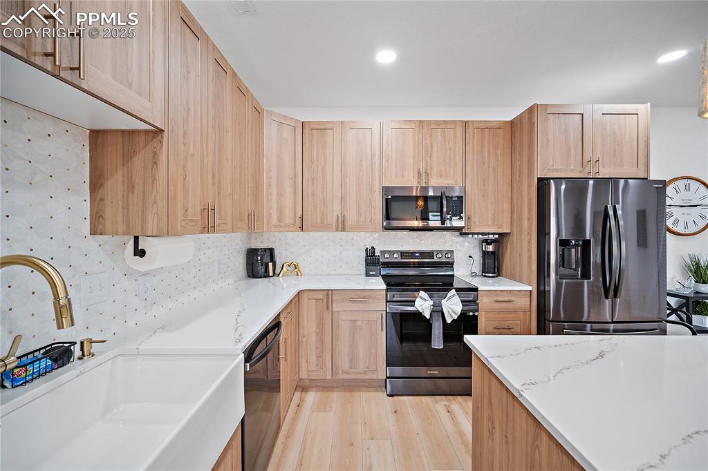 Image 24 of 47: Kitchen featuring light wood-type flooring, a sink, appliances with stainle