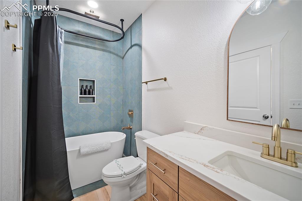 Image 36 of 47: Bathroom with vanity, toilet, a shower with shower curtain, wood finished f