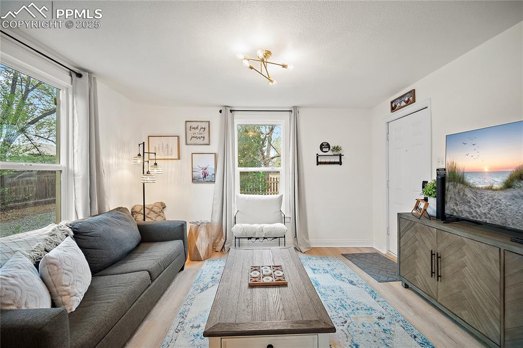 Image 4 of 47: Living area featuring baseboards, a textured ceiling, light wood finished f