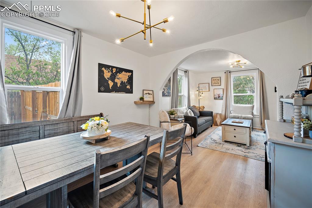 Image 8 of 47: Dining area featuring arched walkways, a notable chandelier, and light wood