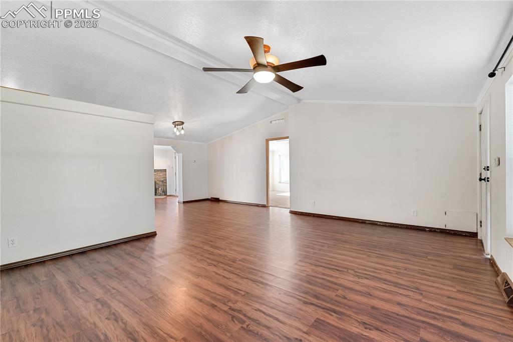 Image 10 of 46: Unfurnished room featuring ceiling fan, wood finished floors, and crown mol