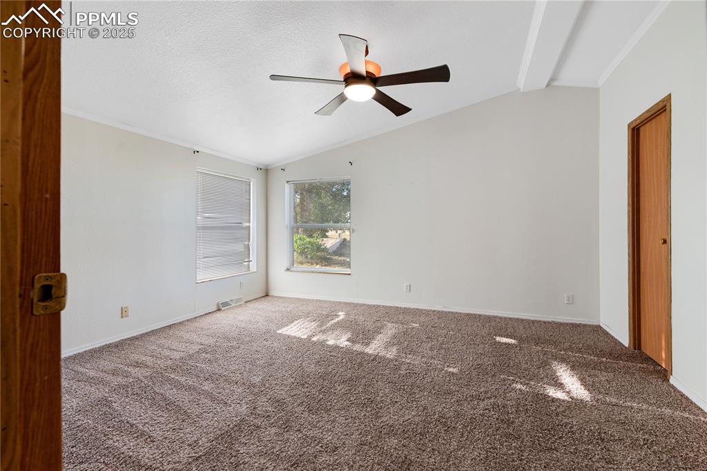 Image 14 of 46: Spare room with lofted ceiling, crown molding, carpet, and a ceiling fan