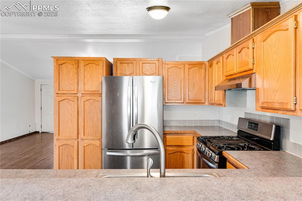Image 28 of 46: Kitchen with stainless steel appliances, crown molding, a textured ceiling,