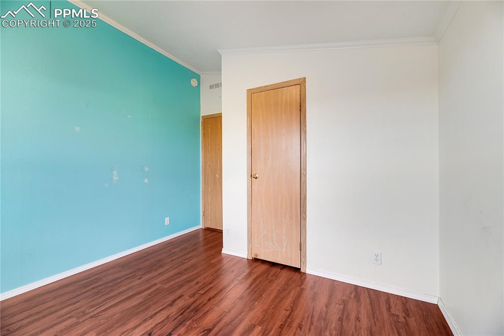 Image 33 of 46: Unfurnished bedroom with crown molding, wood finished floors, and a closet