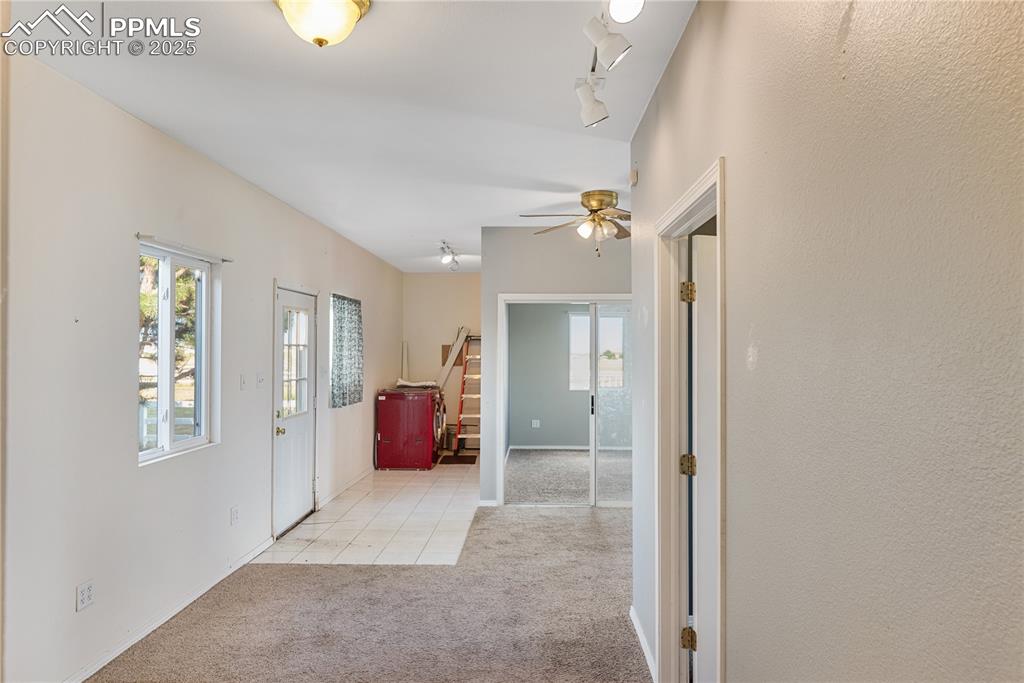 Image 34 of 46: Carpeted entrance foyer with stairs, ceiling fan, tile patterned floors, an
