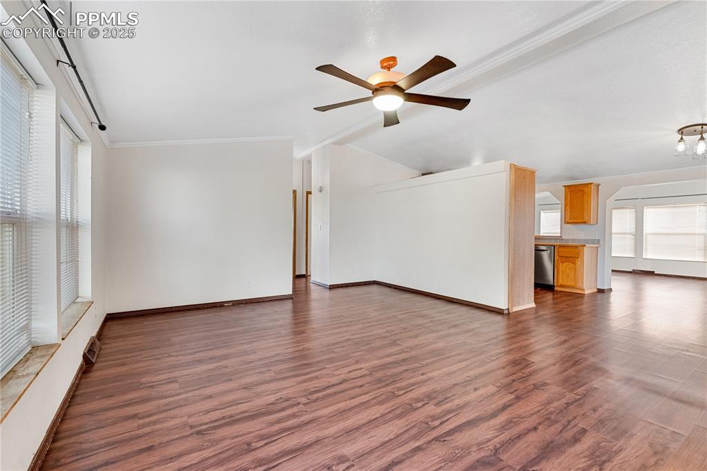 Image 9 of 46: Unfurnished living room with crown molding, dark wood-style flooring, a cei