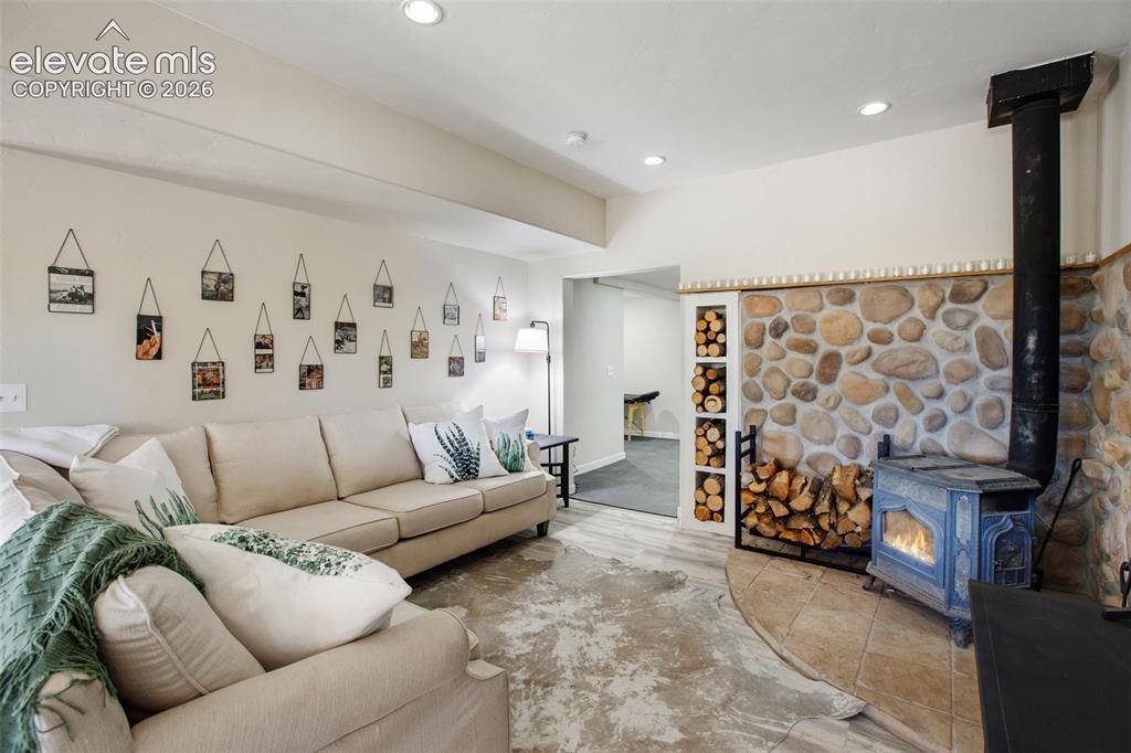 Image 11 of 46: Lower level living room with wood burning fireplace