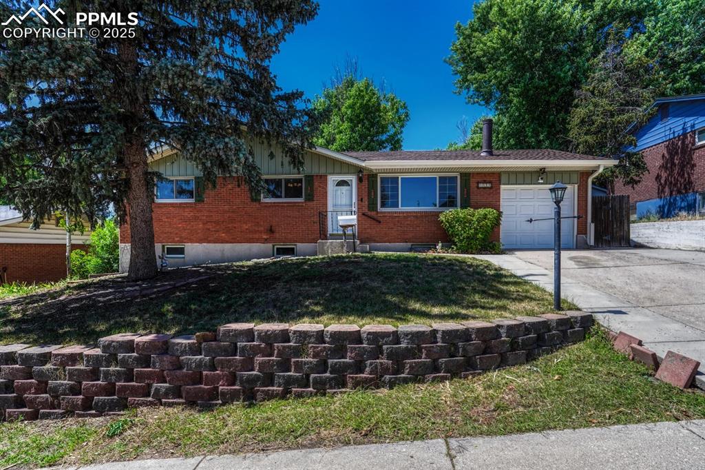 Caption: Single story home featuring an attached garage, driveway, and brick siding