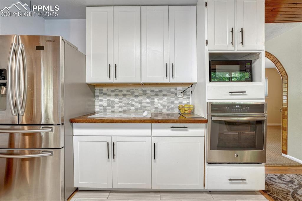 Image 11 of 38: Kitchen featuring appliances with stainless steel finishes, white cabinets,
