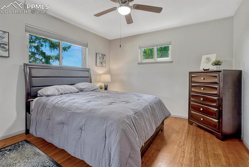 Image 12 of 38: Bedroom with wood finished floors and a ceiling fan