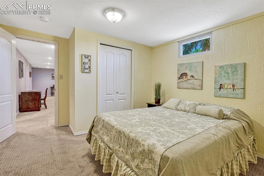 Image 18 of 38: Carpeted bedroom with a textured wall, a textured ceiling, and a closet