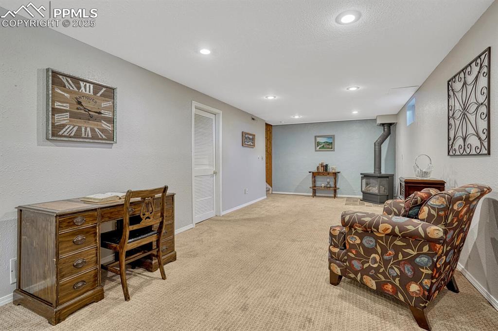 Image 22 of 38: Carpeted home office with a wood stove, recessed lighting, and a textured w